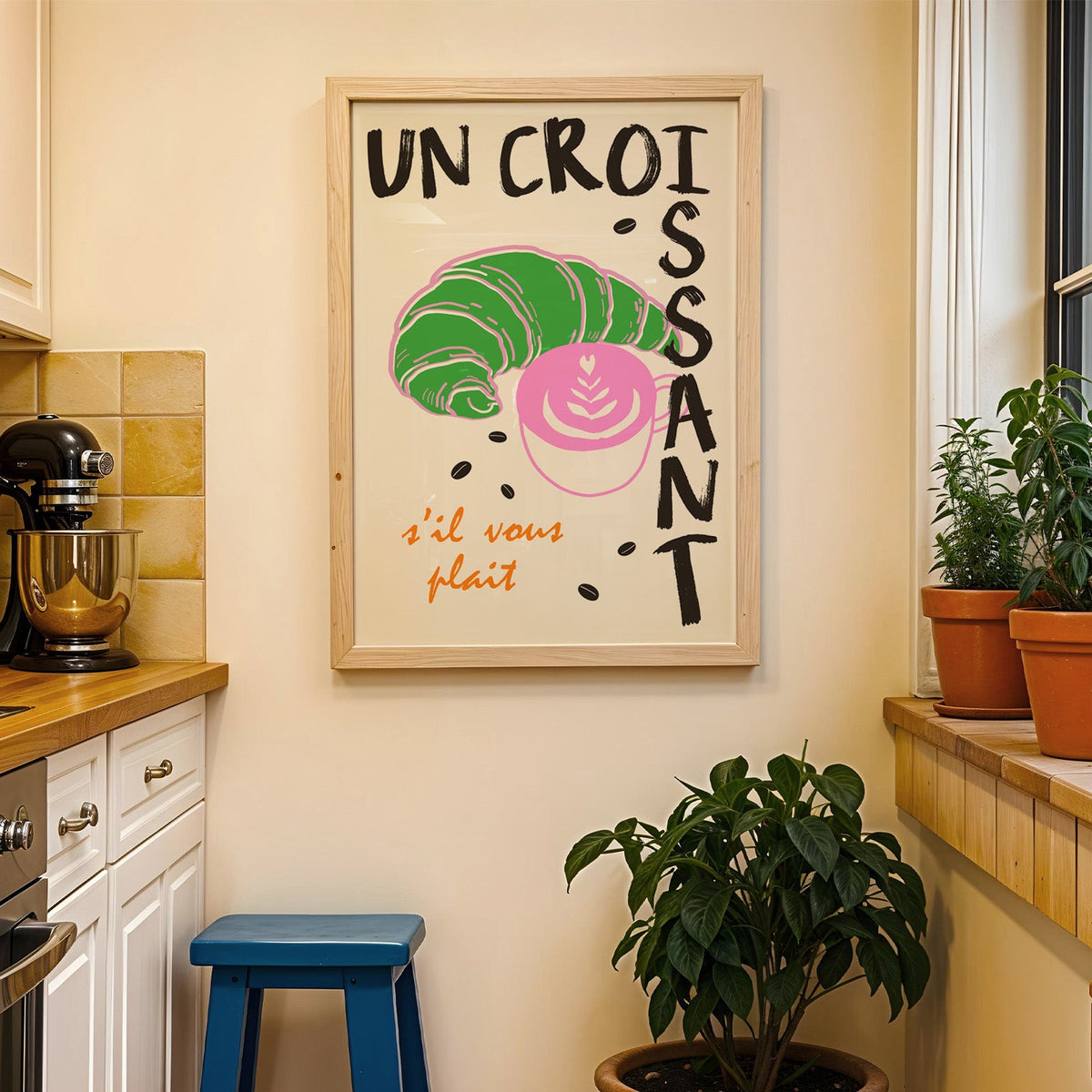 Un croissant french bakery print in a wood frame on a yellow tiled kitchen wall