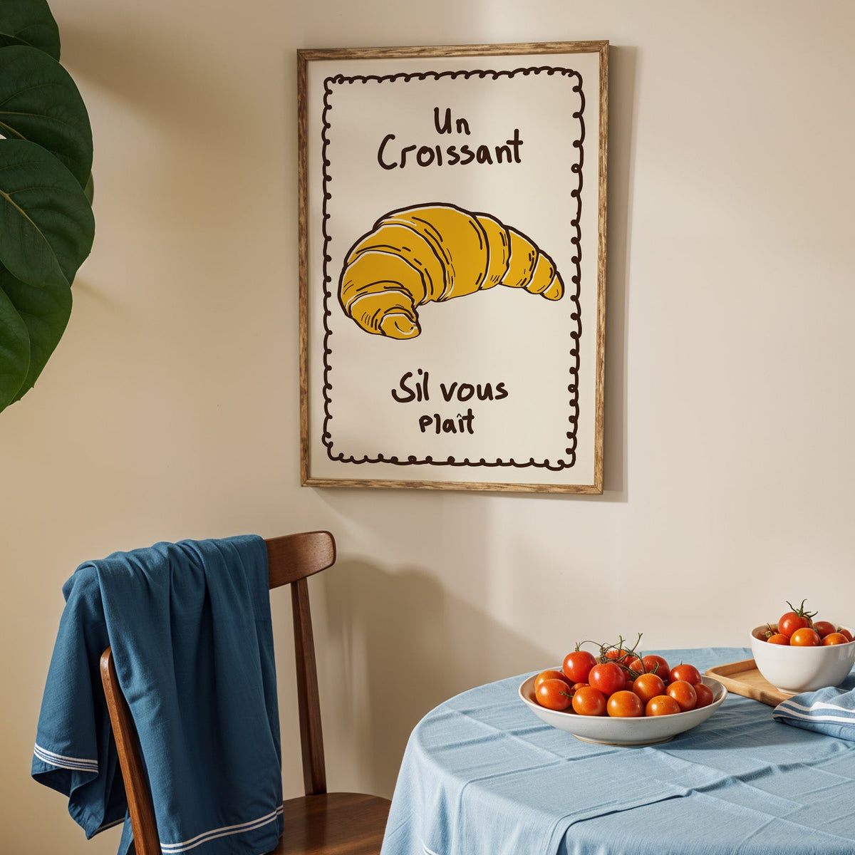 Un croissant yellow bakery print in an oak frame above a blue linen table
