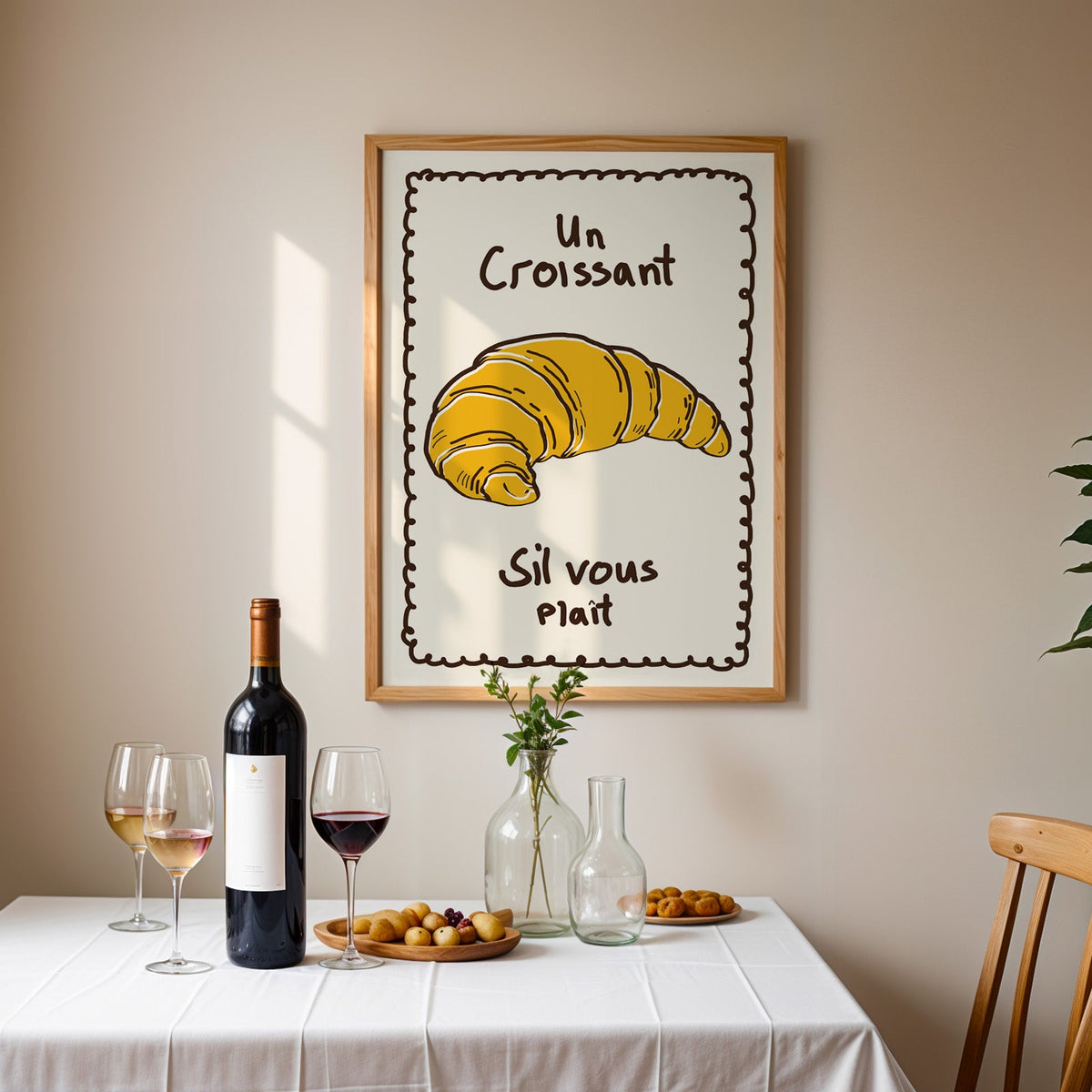 Un croissant yellow bakery print in an oak frame above a table laid with red wine