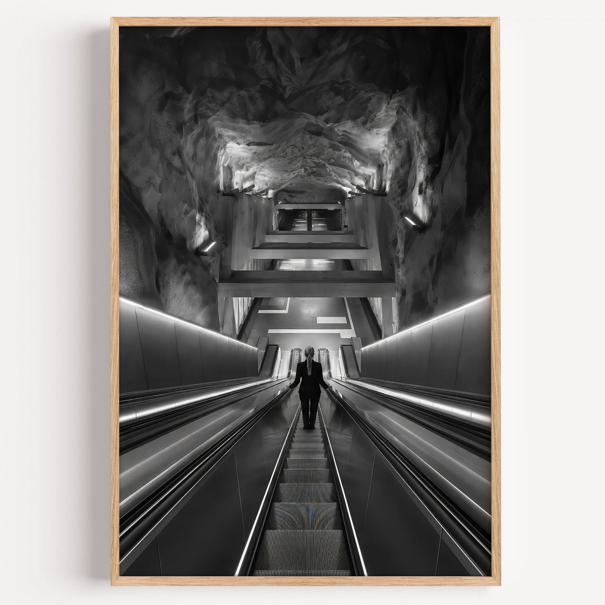Black and white rock cave subway escalator print in a light oak frame on a plain white wall