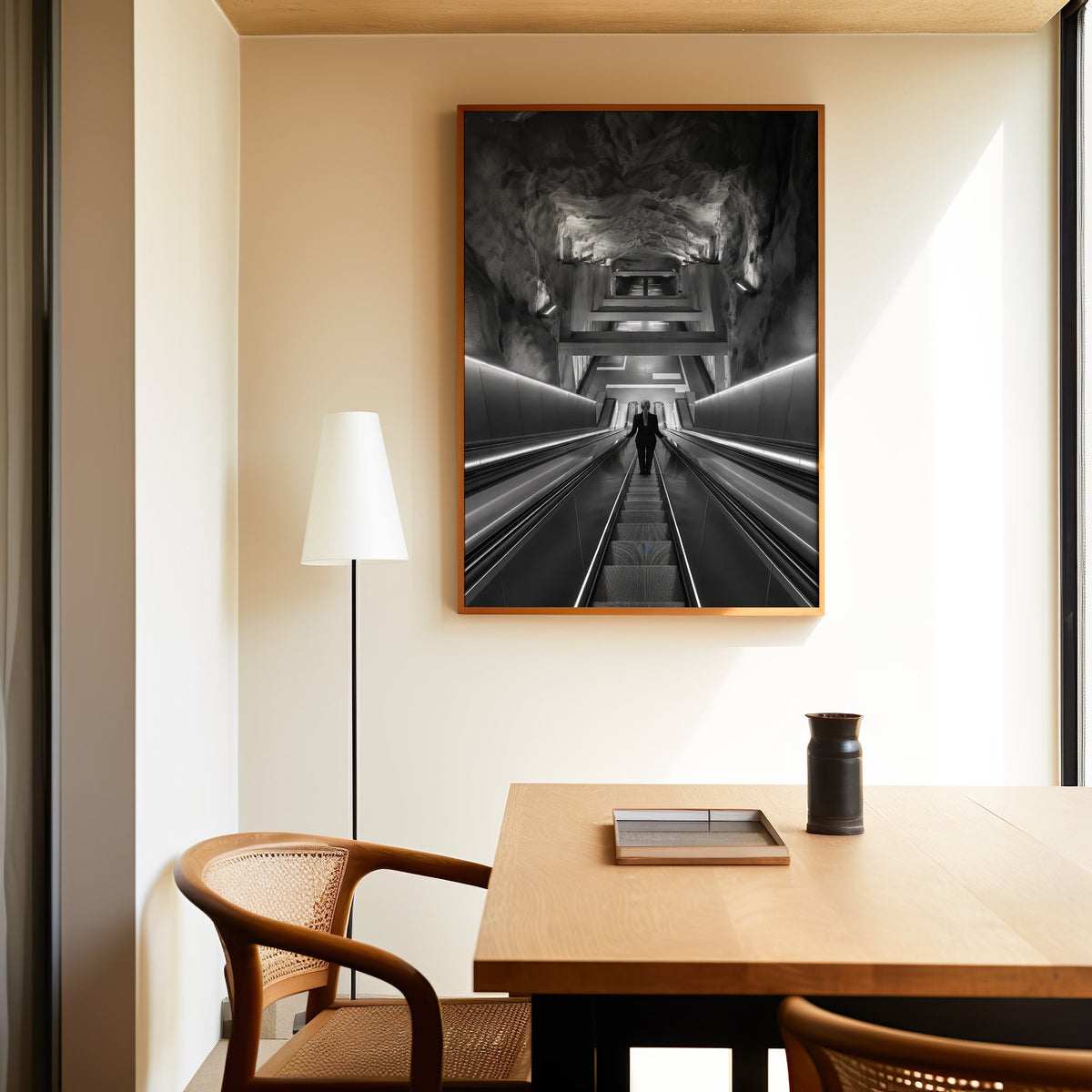 Black and white rock cave subway escalator print in an oak frame above a dining table and cane chair