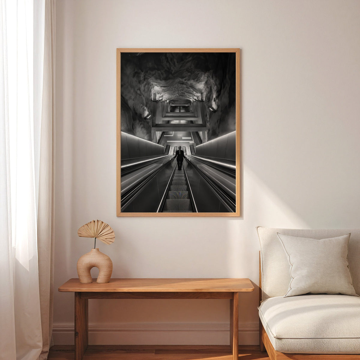 Black and white rock cave subway escalator print in an oak frame above a narrow console with an arched vase