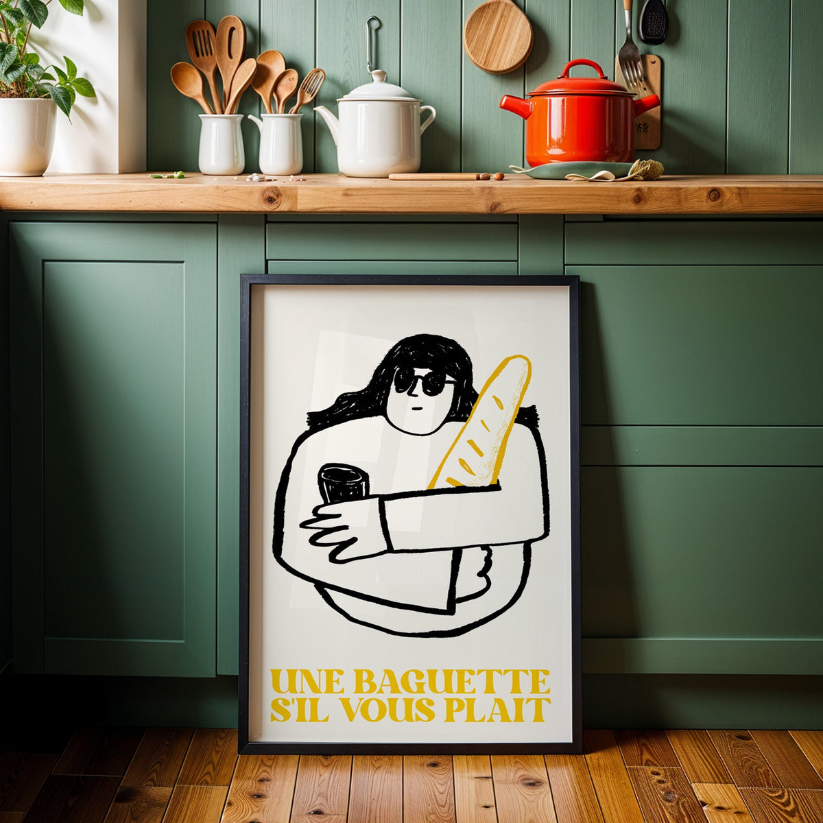 Une baguette french market print in a black frame against sage green cabinets