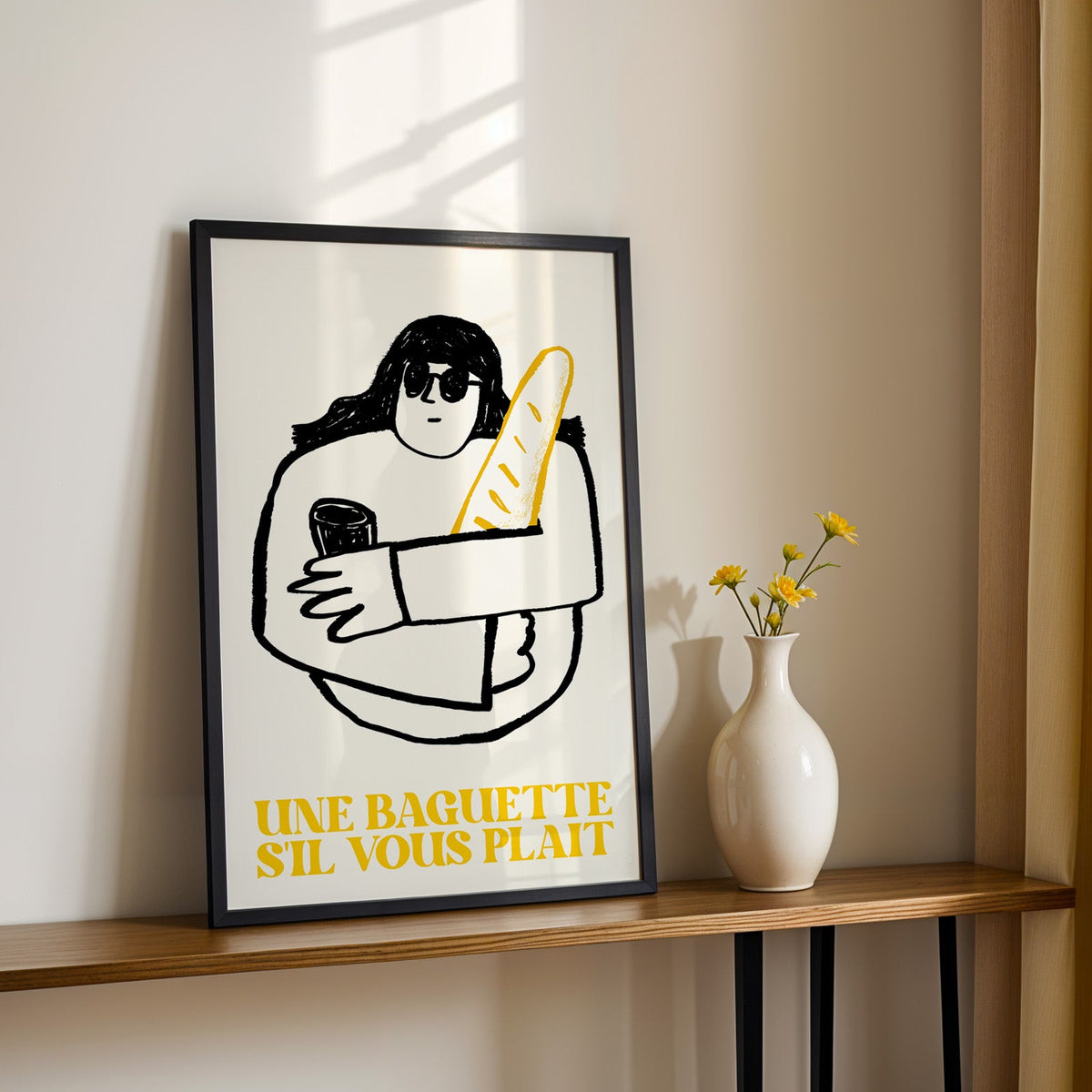 Une baguette french market print in a black frame on a console table with daisies