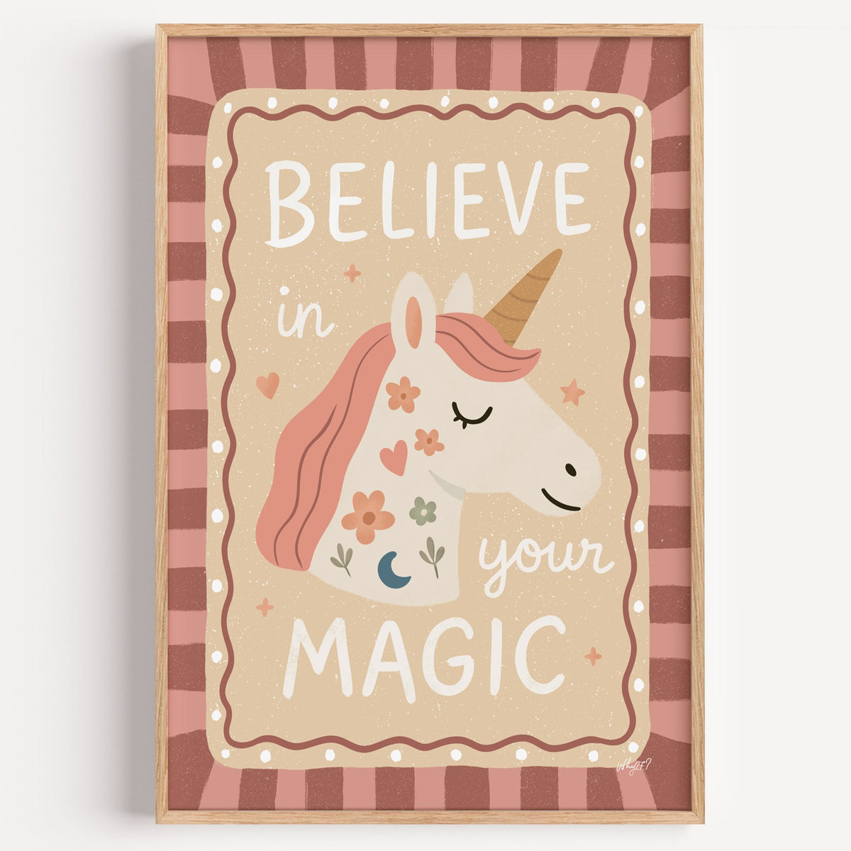 Unicorn head with magic quote nursery print in a light oak frame on a plain white wall