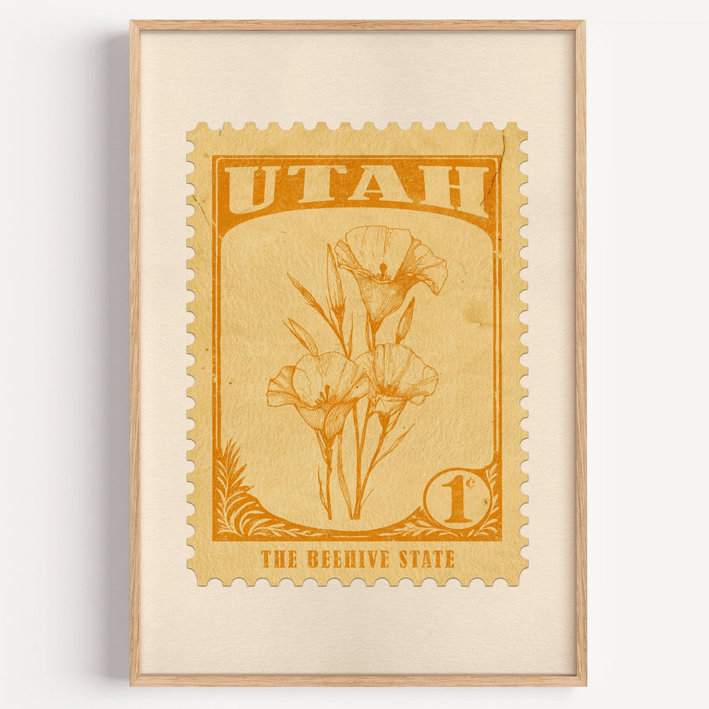 Utah state flower stamp print in orange gold on pale yellow, light oak frame on a plain white wall