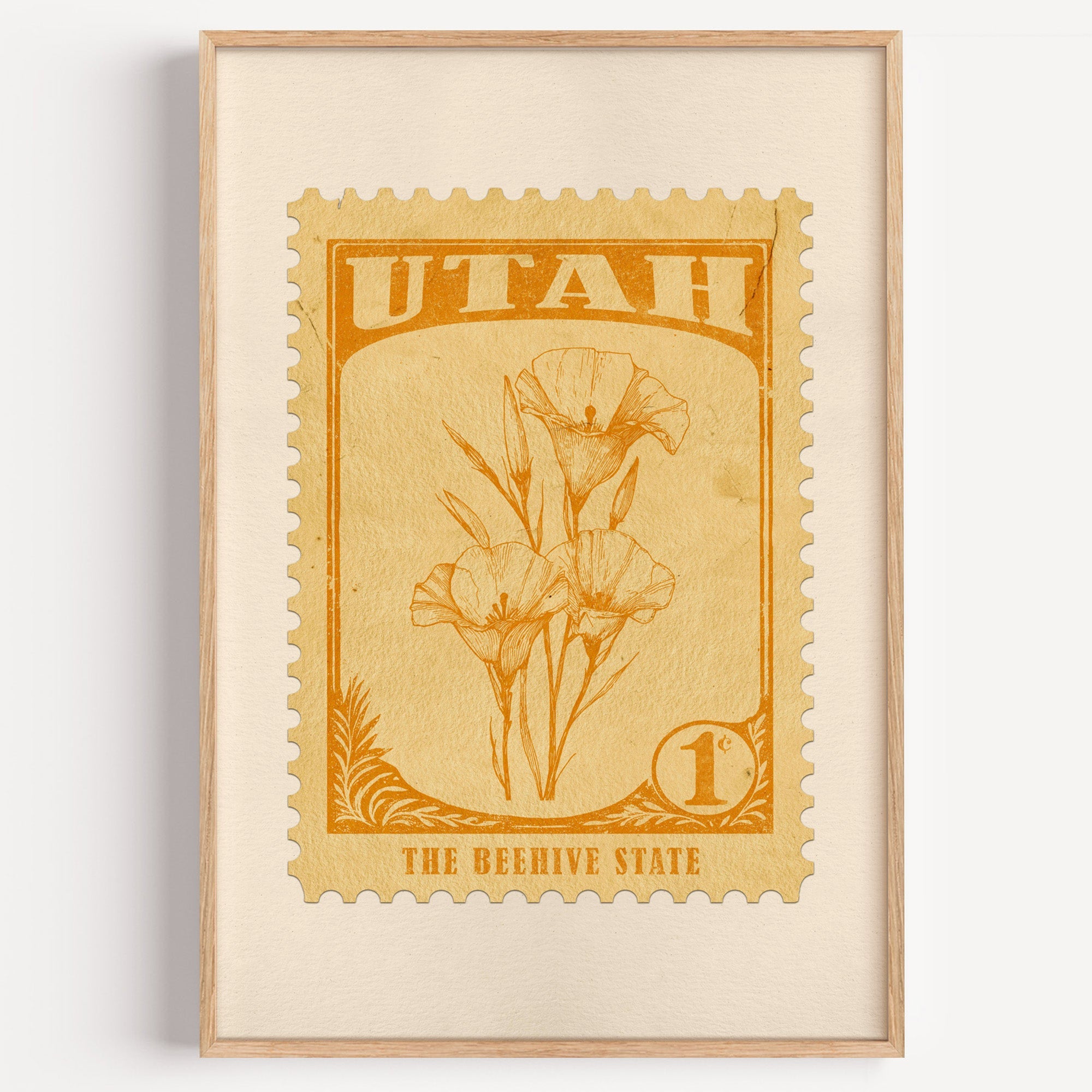 Utah state flower stamp print in orange gold on pale yellow, light oak frame on a plain white wall