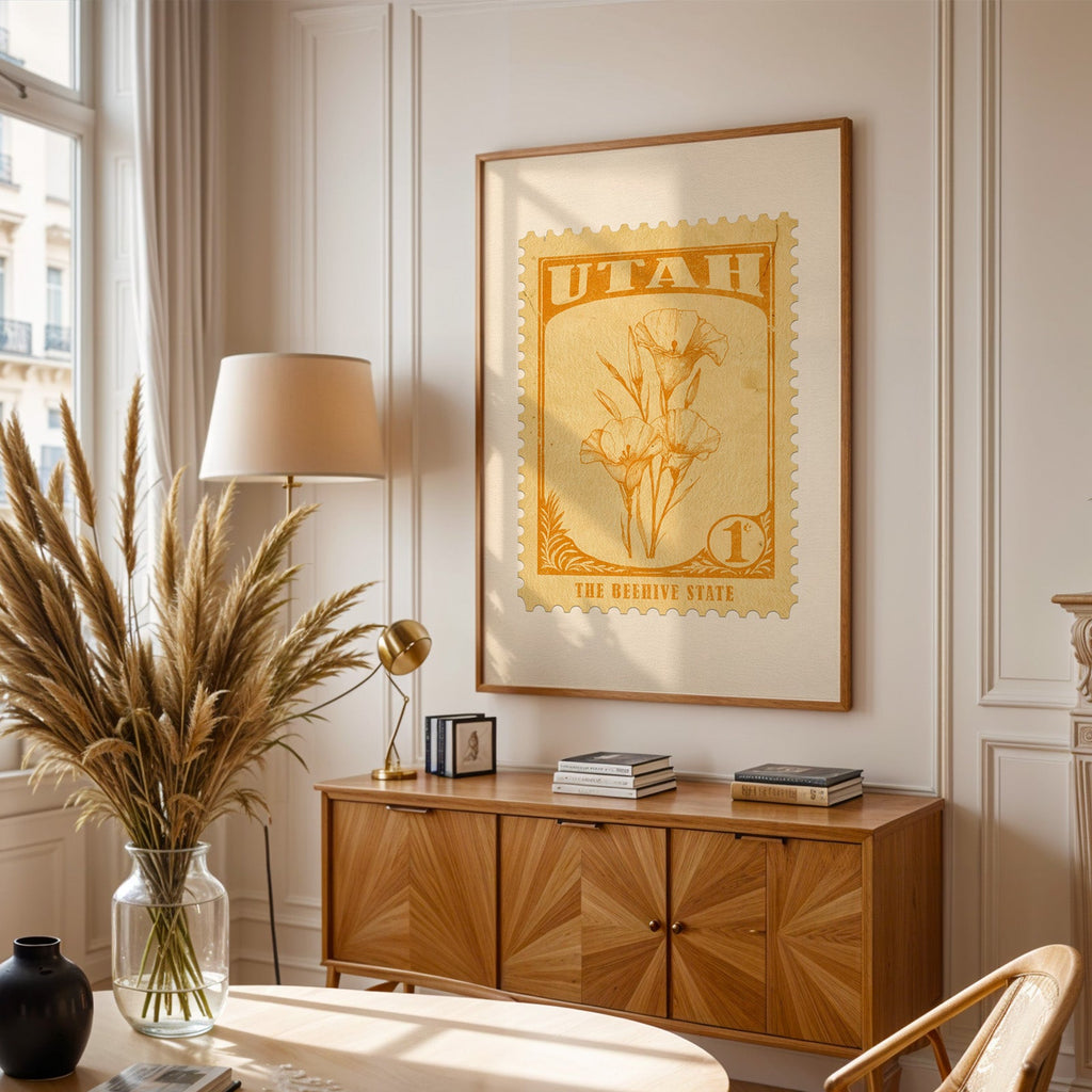 Utah stamp print framed above a wooden sideboard, pampas grass in a glass vase and a floor lamp