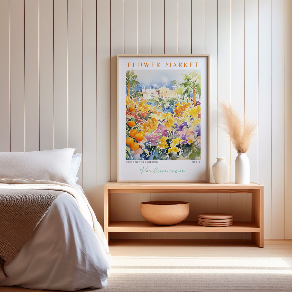 Valencia flower market print in an oak frame on a wood bench against a white shiplap bedroom wall with pampas grass