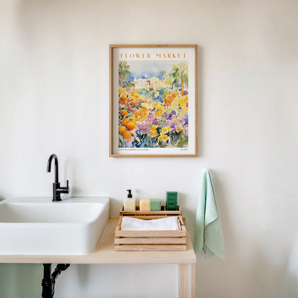 Valencia flower market print in an oak frame above a white bathroom sink with folded towels