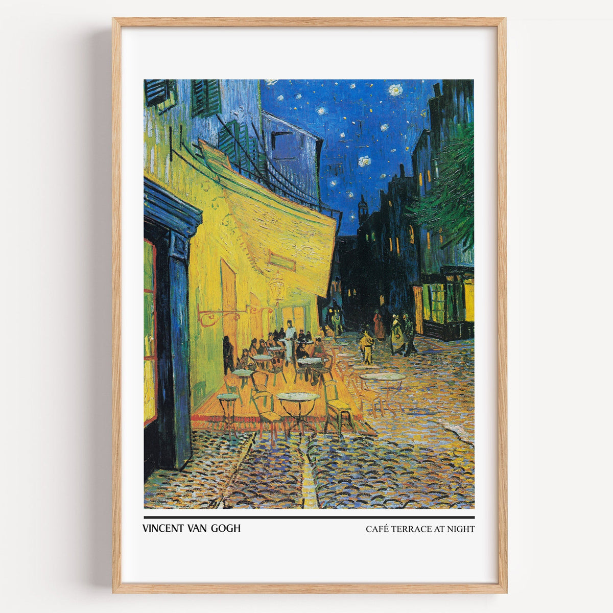 Café Terrace at Night by Van Gogh print in a light oak frame on a plain white wall