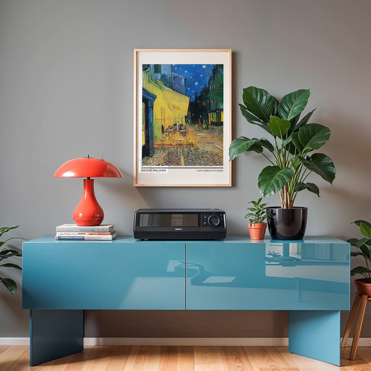 Van Gogh night café poster in an oak frame above a teal sideboard with a red lamp