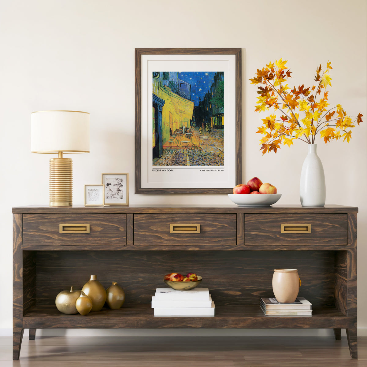 Café Terrace at Night print in a walnut frame above a console with autumn branches