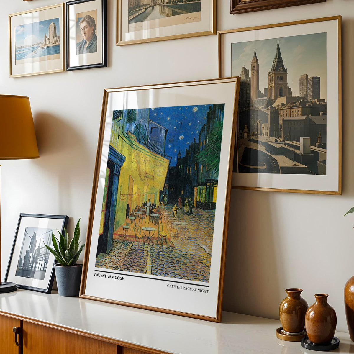 Van Gogh café print shown in a gold frame leaning on a sideboard in a gallery wall