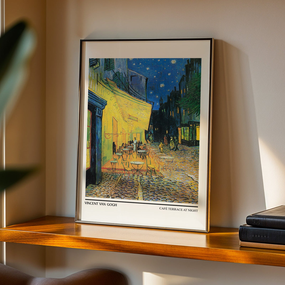 Café Terrace at Night print in a black frame on a walnut shelf in evening light