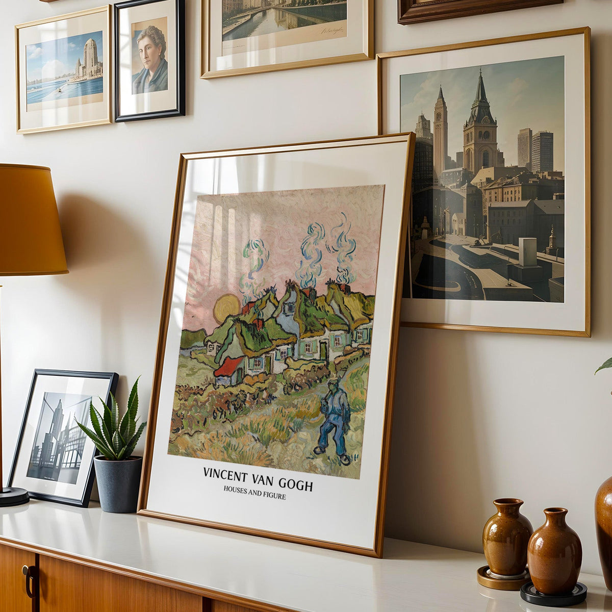Van Gogh cottage print shown in a gold frame leaning on a sideboard in a gallery wall