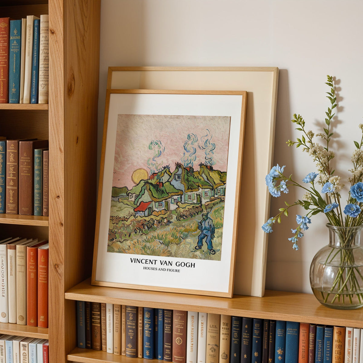 Van Gogh landscape in an oak frame leaning on a bookshelf beside blue flowers