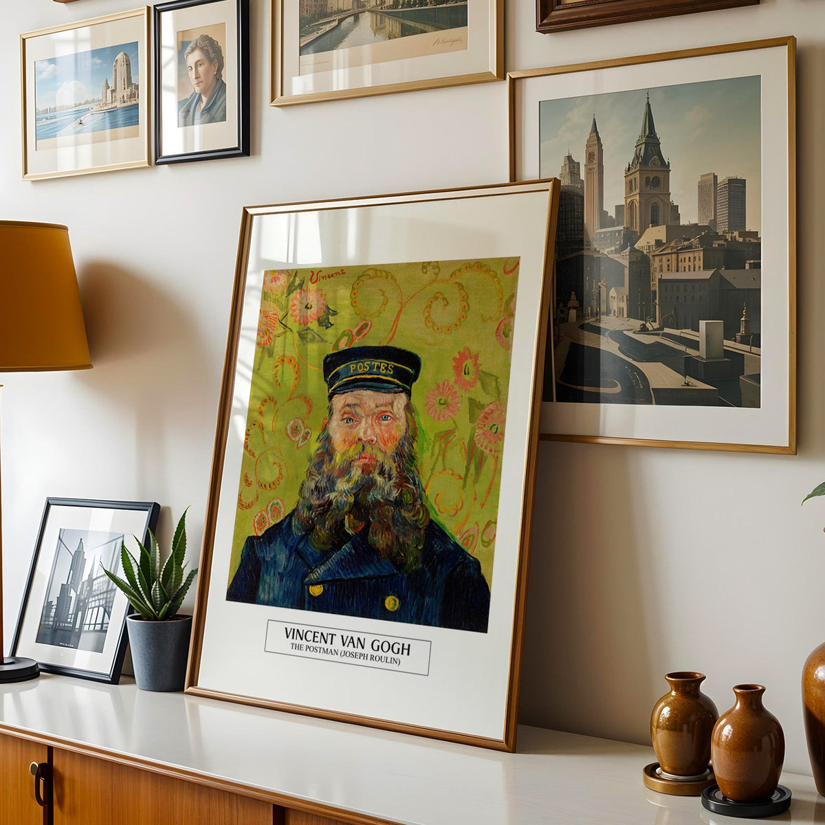 Van Gogh postman print shown in a gold frame leaning on a sideboard in a gallery wall