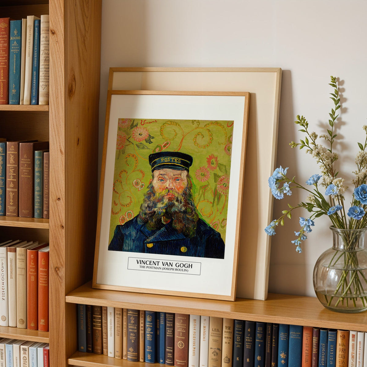 Van Gogh portrait in an oak frame leaning on a bookshelf beside blue flowers