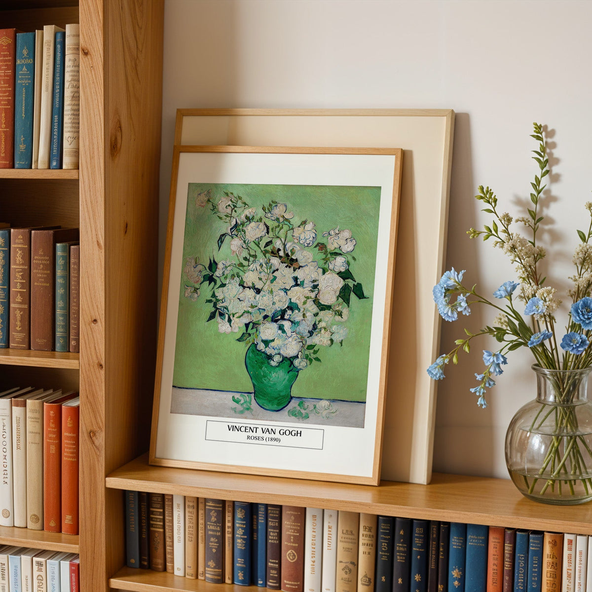 Van Gogh flower print in an oak frame leaning on a bookshelf beside blue flowers