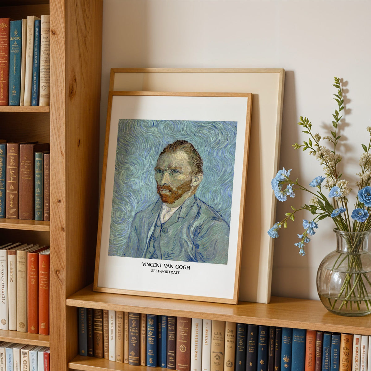 Van Gogh self-portrait in an oak frame leaning on a bookshelf beside blue flowers