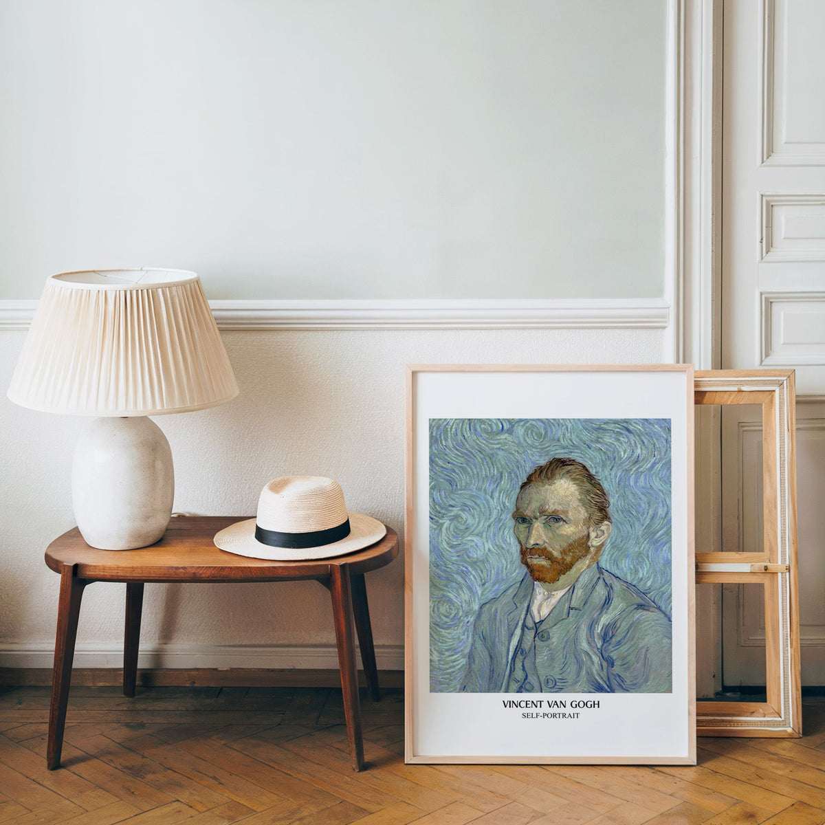 Van Gogh portrait poster in a light wood frame leaning by a bench and panama hat