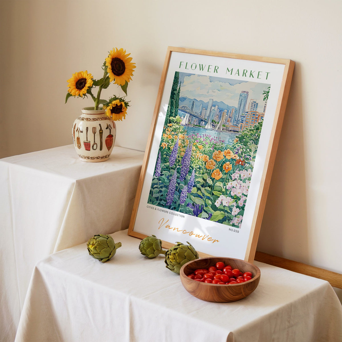 Vancouver flower market print in an oak frame leaning on a linen-draped table beside a vase of sunflowers