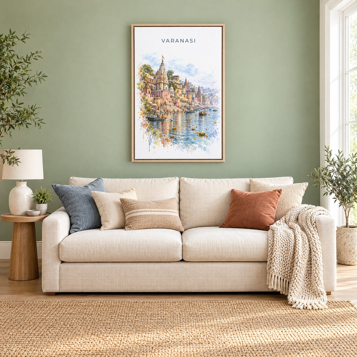 Varanasi watercolor print as a natural floater canvas above a cream linen sofa on a sage green wall