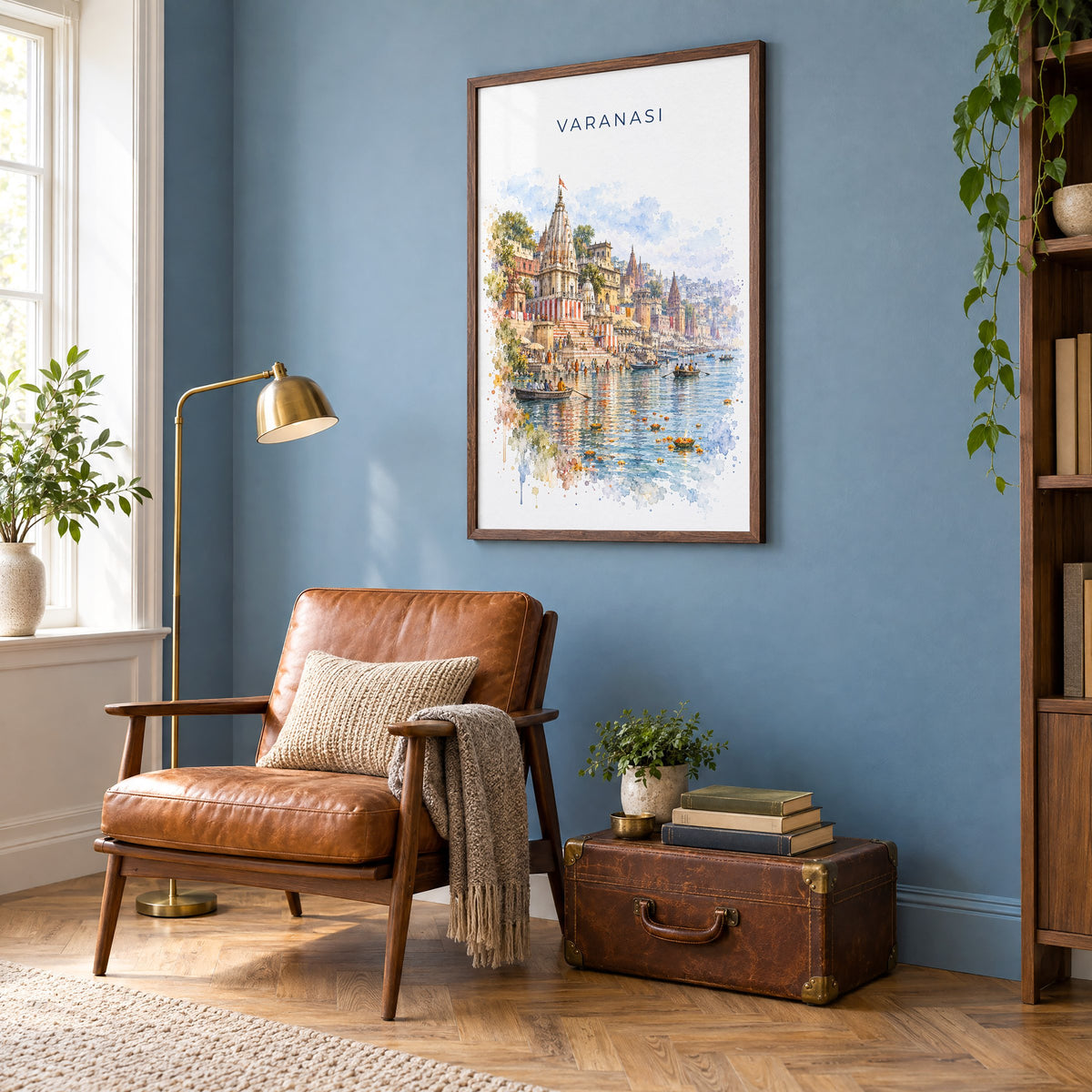 Varanasi watercolor print in a walnut frame on a blue wall above a leather armchair in a reading nook