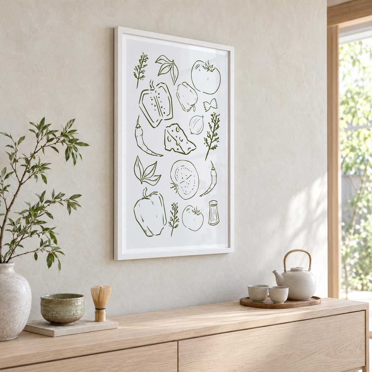 Olive line veggies and farfalle pattern in a white frame above a pale wood console with a matcha tea set