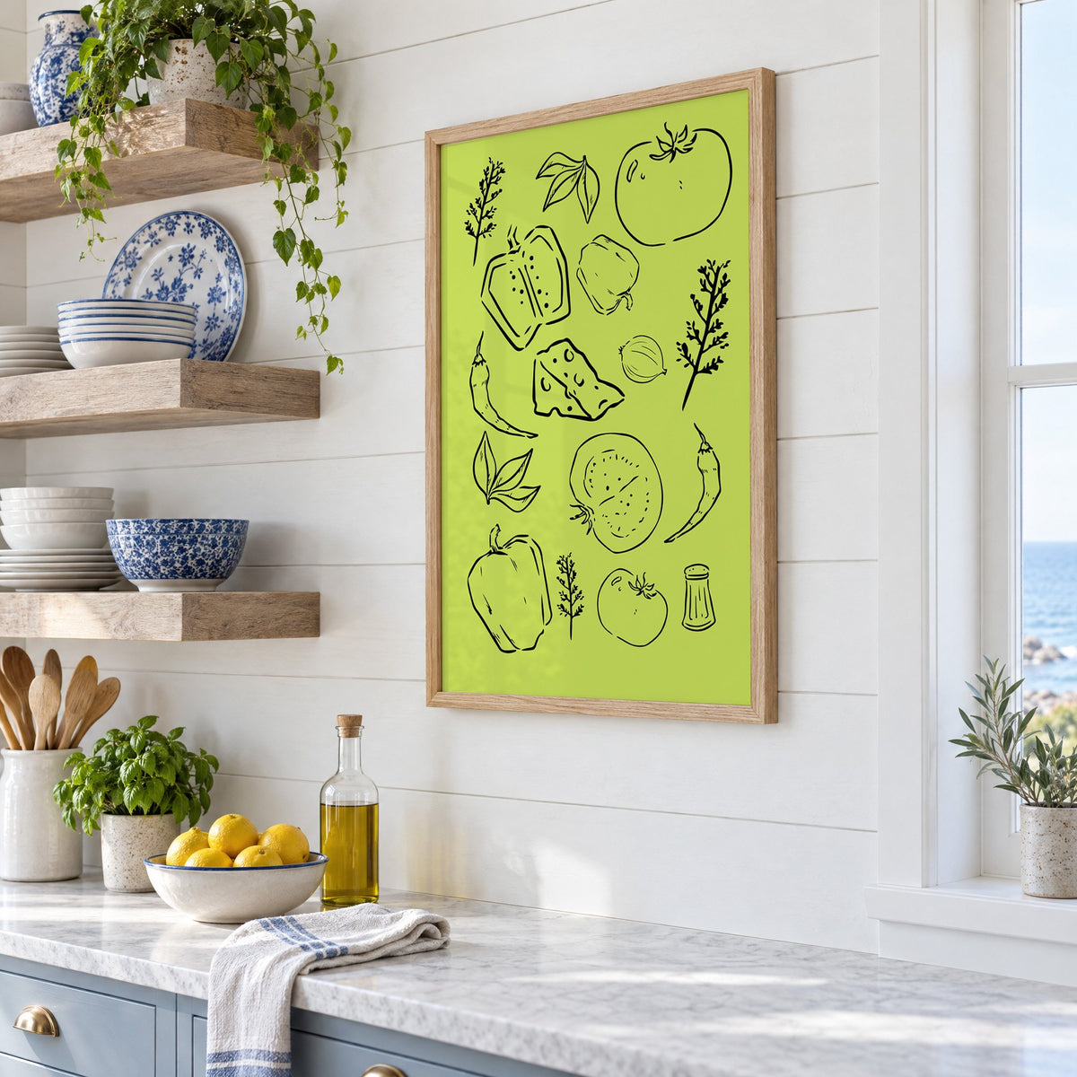 Veggie and cheese line art on green print in an oak frame in a white coastal kitchen beside blue and white plates
