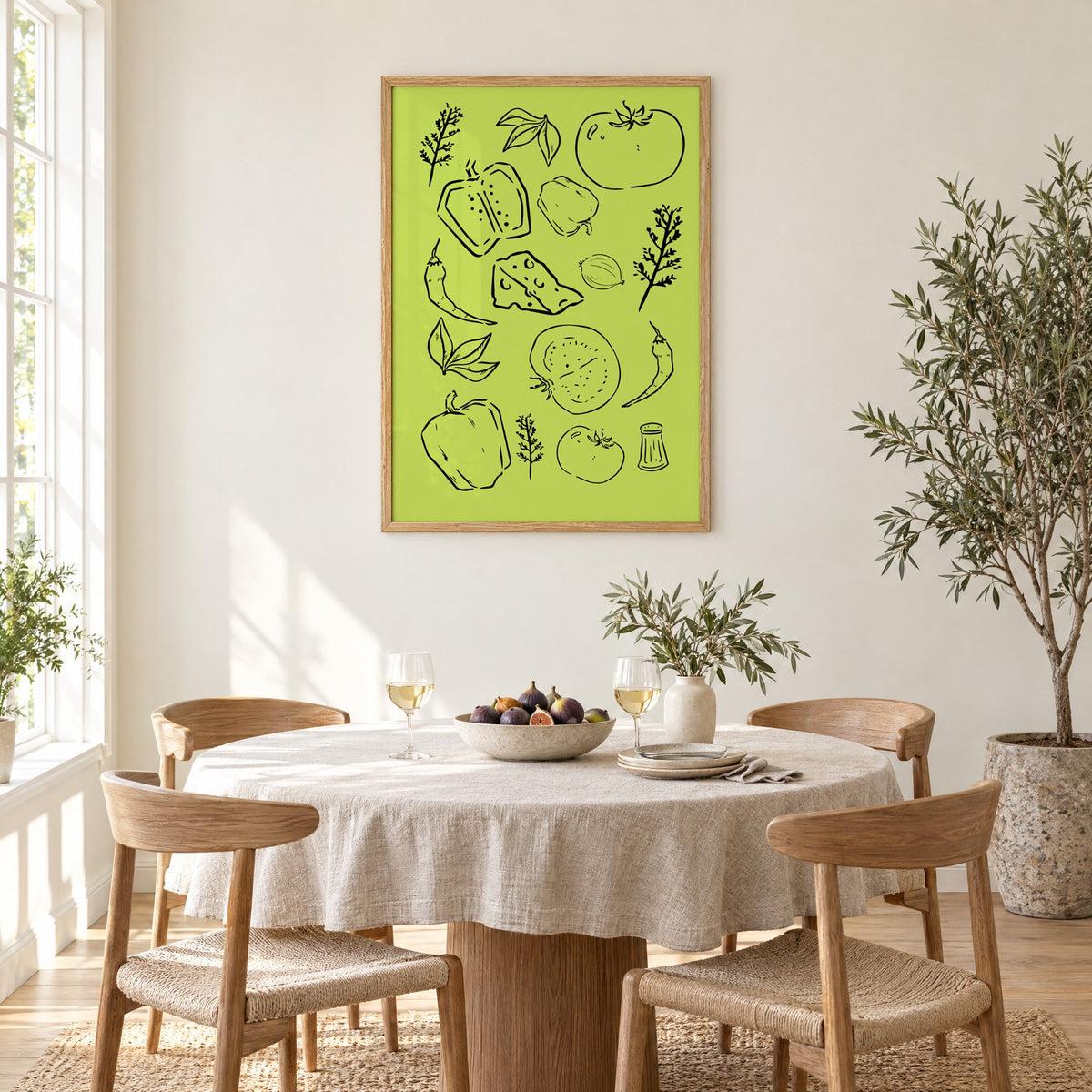 Veggie and cheese line art on green print in an oak frame above a round linen-covered dining table with figs and wine