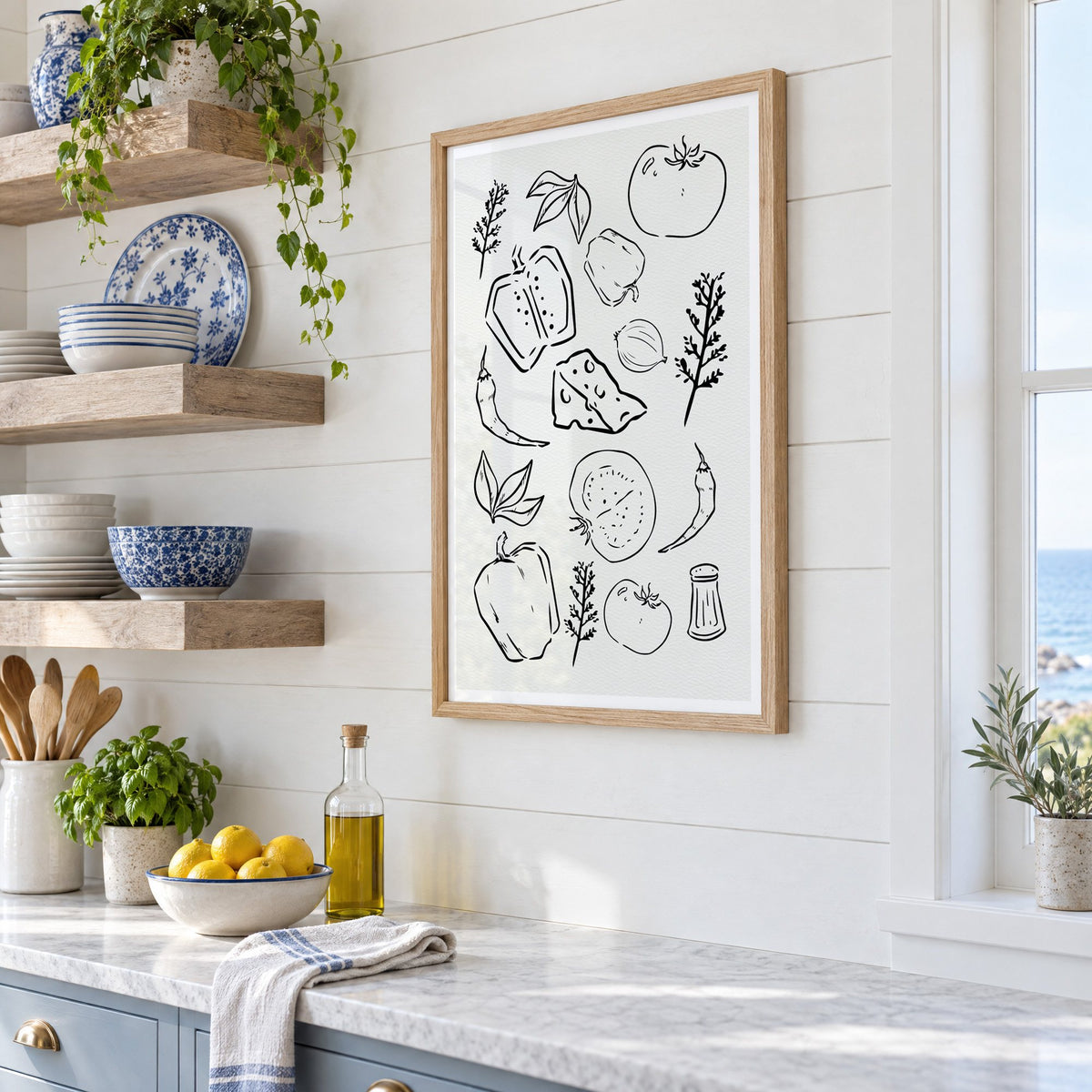 Veggie and cheese sketch on ivory print in an oak frame in a white coastal kitchen beside blue and white plates