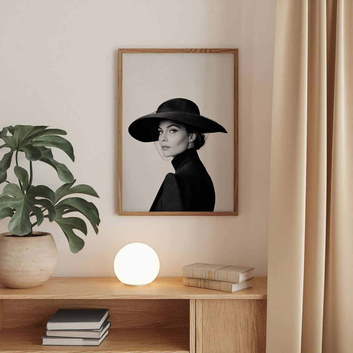 Woman in wide brim hat and mesh veil print in a walnut frame above an oak cabinet with a glowing globe lamp