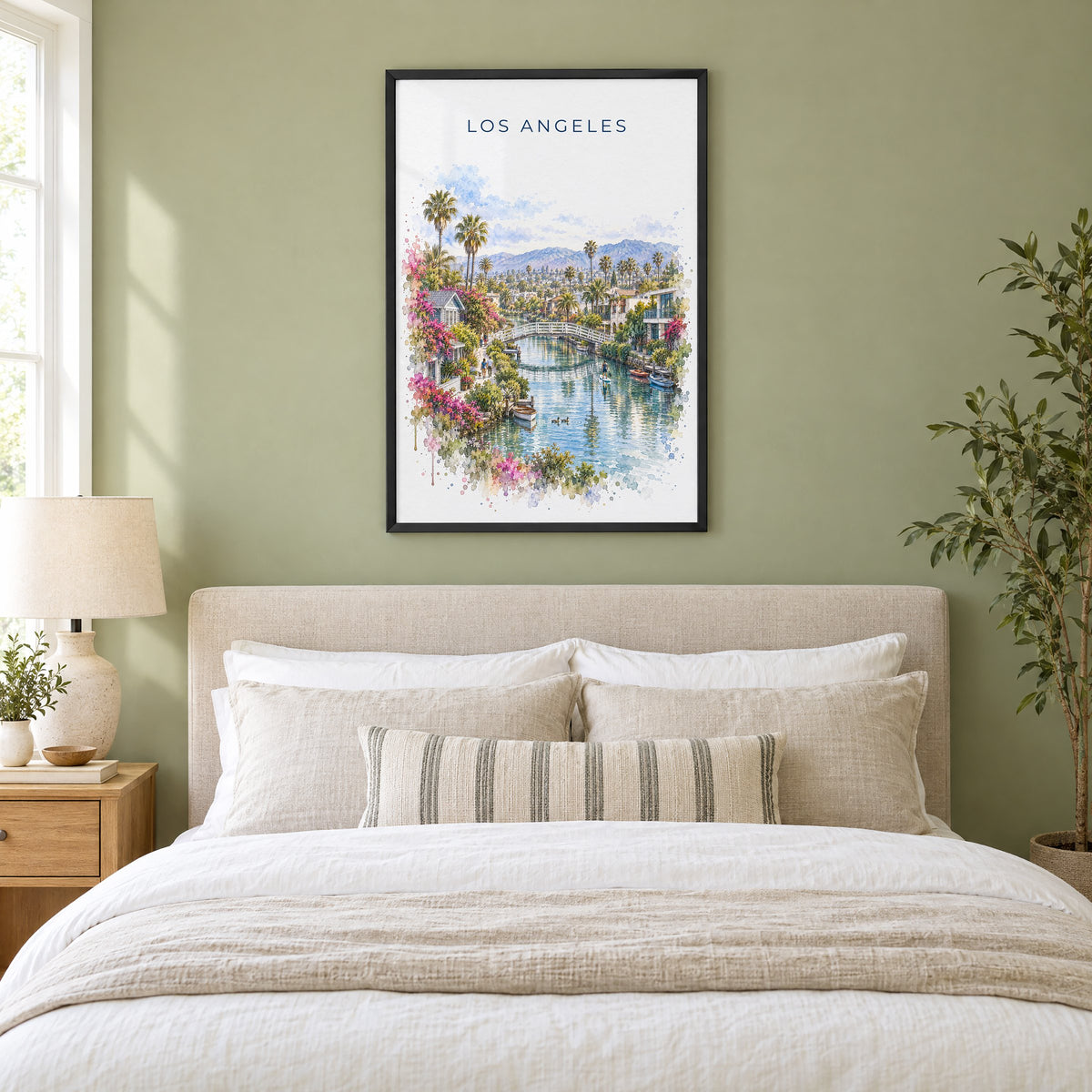 Venice Canals Los Angeles watercolor print in a black frame above an upholstered headboard in a sage green bedroom