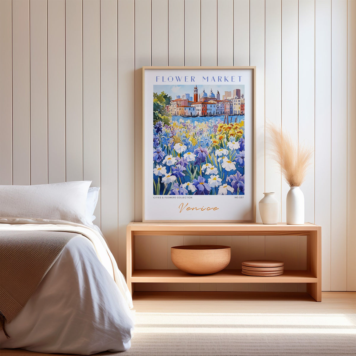 Venice flower market print in an oak frame on a wood bench against a white shiplap bedroom wall with pampas grass