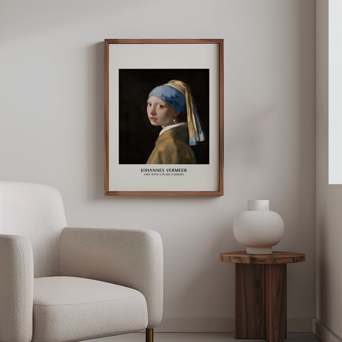 Vermeer portrait print in a slim walnut frame above a bouclé armchair