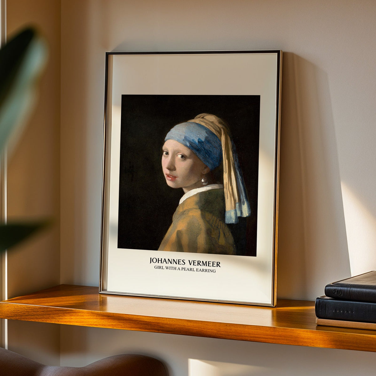 Girl with a Pearl Earring print in a black frame on a walnut shelf in evening light