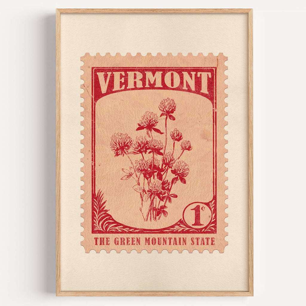 Vermont state flower stamp print in red on pale peach, light oak frame on a plain white wall