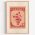 Vermont state flower stamp print in red on pale peach, light oak frame on a plain white wall