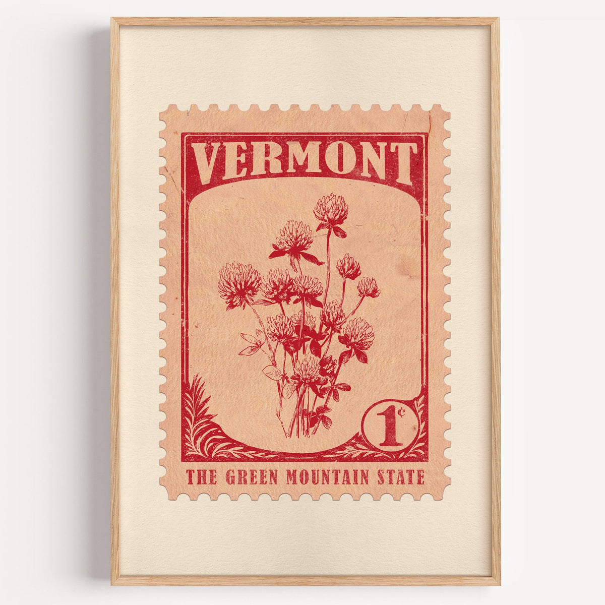 Vermont state flower stamp print in red on pale peach, light oak frame on a plain white wall