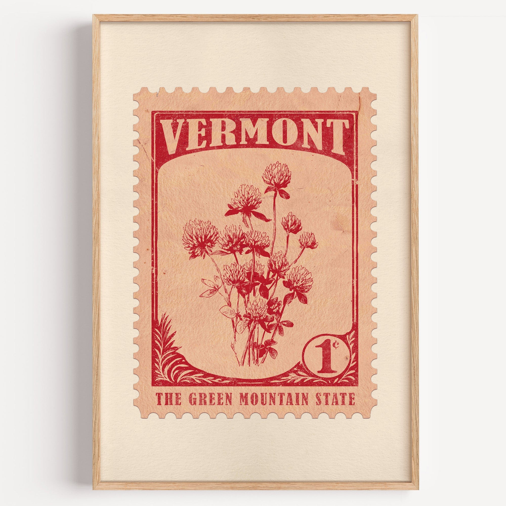 Vermont state flower stamp print in red on pale peach, light oak frame on a plain white wall