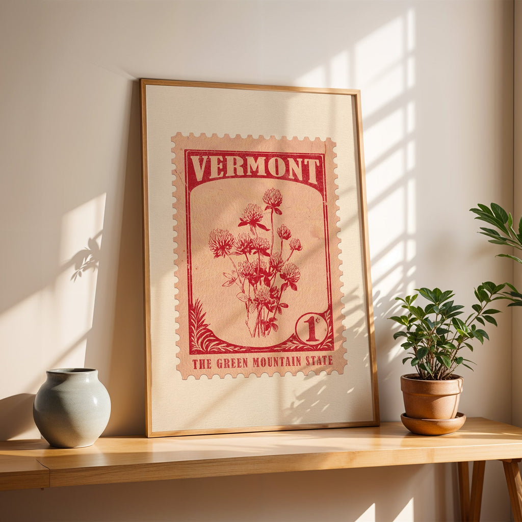 Vermont Red Clover stamp print in a light oak frame leaning on a wooden table beside a stoneware vase