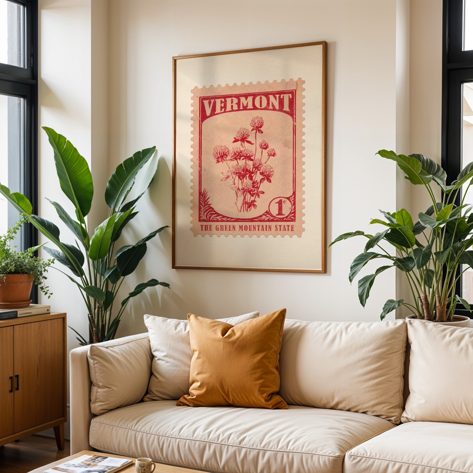 Vermont state flower print framed above a cream sofa with an ochre cushion and large plants either side