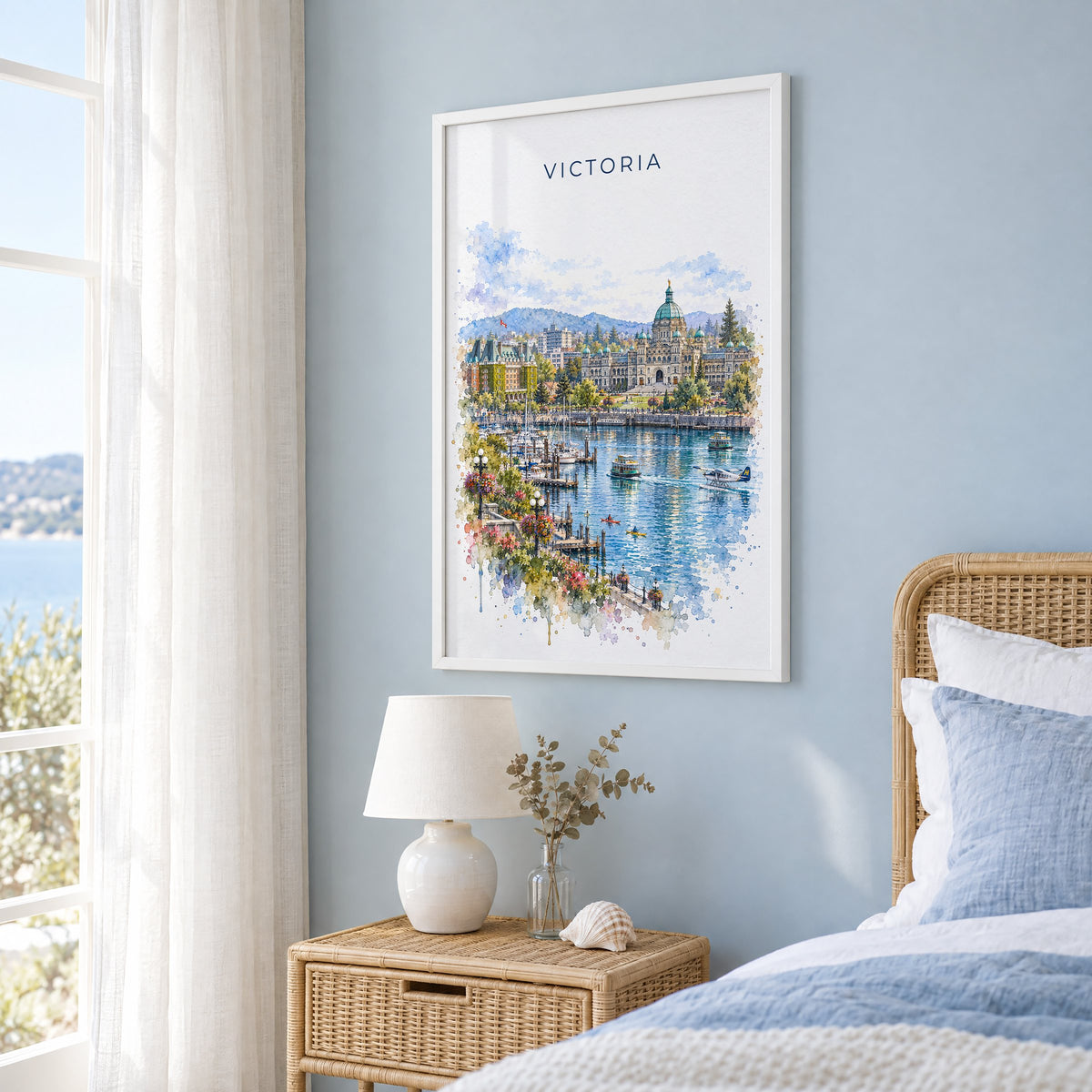 Victoria, Canada watercolor print in a white frame on a pale blue wall beside a rattan bed in a coastal bedroom