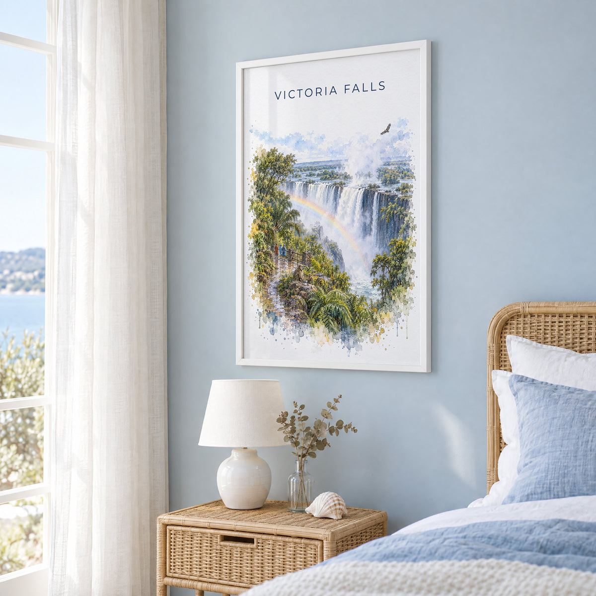 Victoria Falls watercolor print in a white frame on a pale blue wall beside a rattan bed in a coastal bedroom