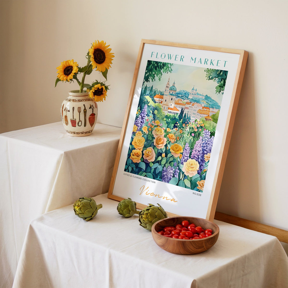 Vienna flower market print in an oak frame leaning on a linen-draped table beside a vase of sunflowers