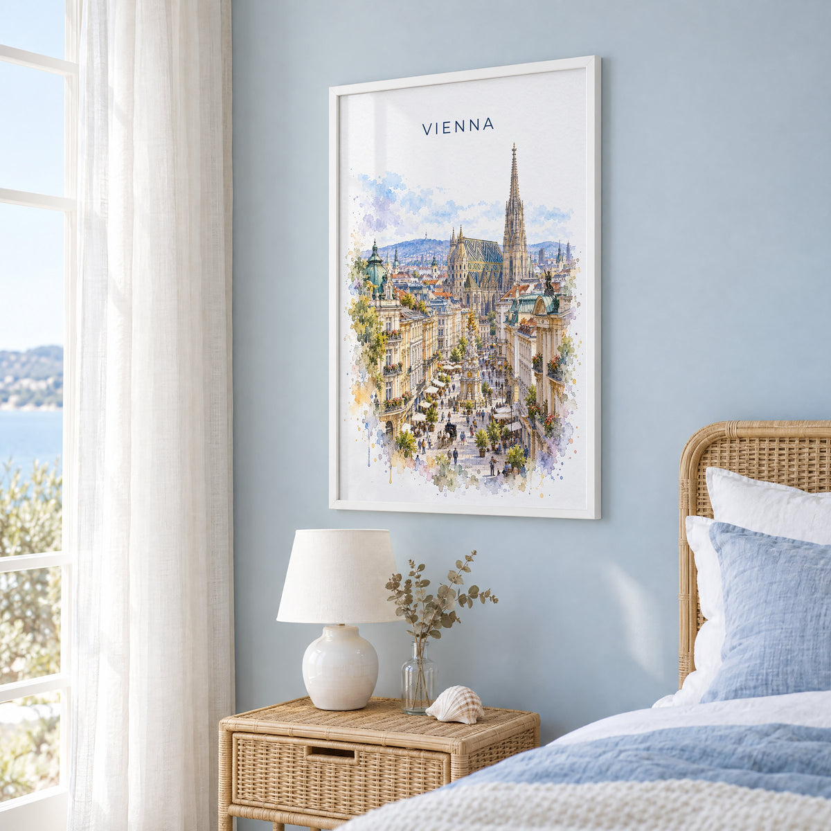 Vienna watercolor print in a white frame on a pale blue wall beside a rattan bed in a coastal bedroom
