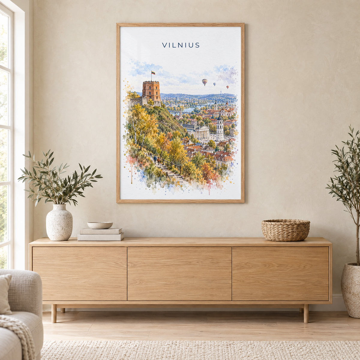 Vilnius watercolor print in an oak frame above a light wood sideboard in a Scandinavian living room