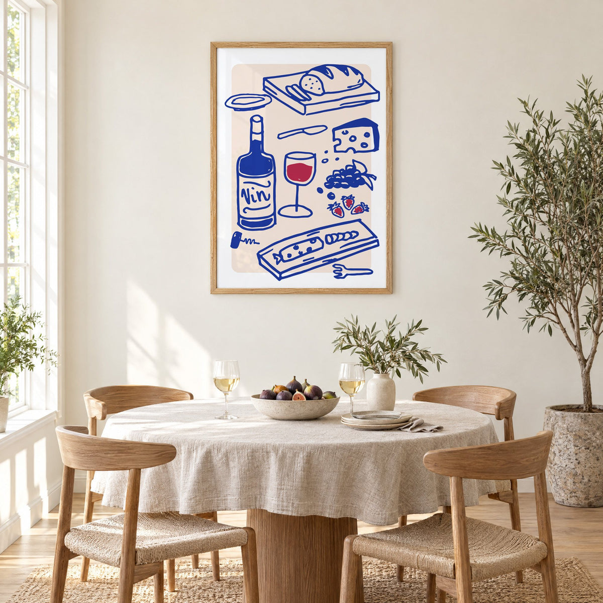 Vin wine and cheese spread print in an oak frame above a round linen-covered dining table with figs and wine